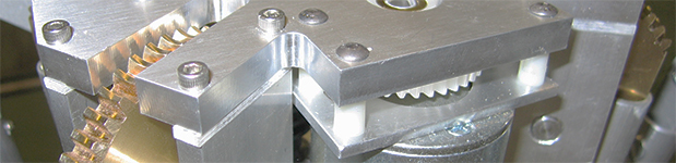 A close-up of a piece of aluminum machinery—there are a variety of cogs contained within the thick metal housing.
