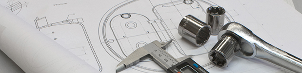 A metal caliper and socket wrench laying on top of black and white design schematics.