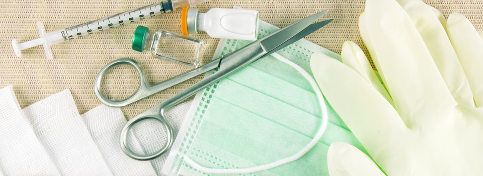 An assortment of medical supplies is depicted, including medication vials, gloves, a mask, scissors, gauze, and syringes.