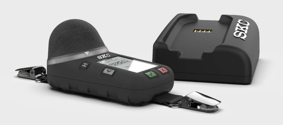 A single SKC NoiseCHEK is shown next to a single charging cradle.