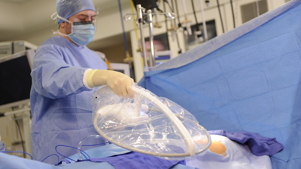 A surgeon is shown holding the RFID Surgical Wand over a patient on an operating table.