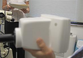 A person is shown holding a handheld device that detects cancer while a person is seen in the background.