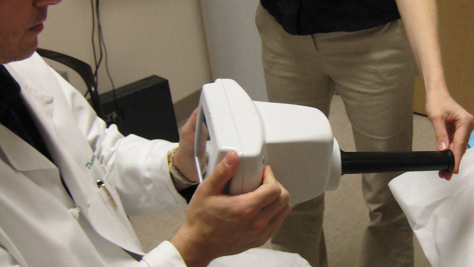 A researcher and doctor are interacting in a clinical setting during an interview and demonstration session.