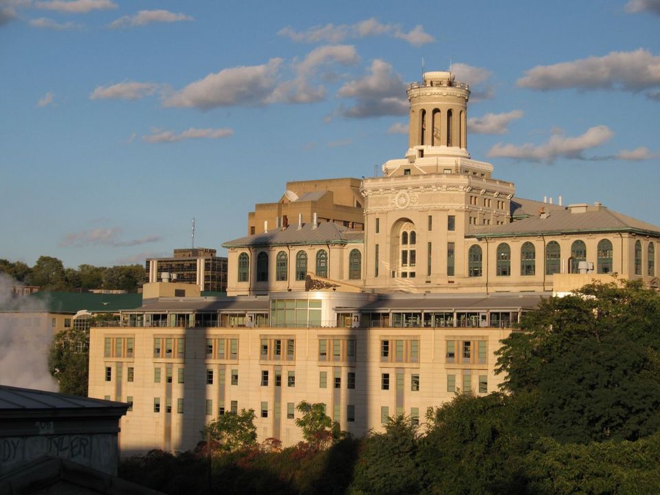 An image of Hamerschlag Hall at CMU, with a blue sky in the background and trees in the foreground.