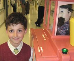 A young boy is shown standing next to a robot that is a toy train with a talking conductor.