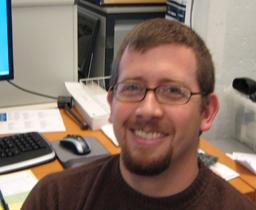 A close-up of Scott with his computer workstation behind him.